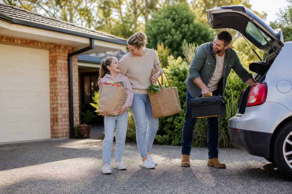 A family unloading the car in the driveway of their home