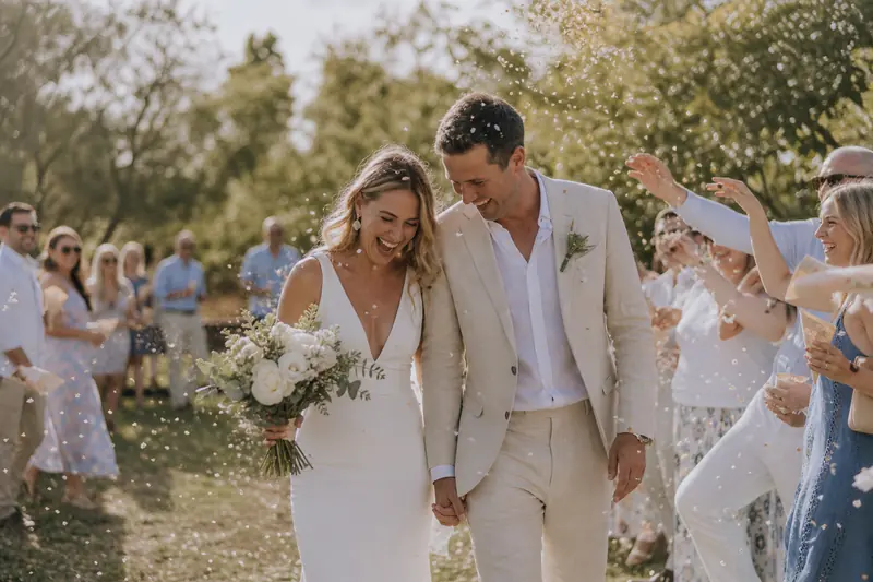 Bride and groom laughing as guests throw confetti over them